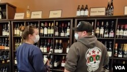 Sarah Robinett and her husband stop by UnWind in Alexandria, Virginia to pick up some bottles of wine. (Photo: Deborah Block / VOA)