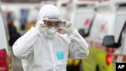 មន្ត្រី​សុខាភិបាល​ម្នាក់​ពាក់​ម៉ាស​និង​ឈុតការពារ​​ពី​ការ​ឆ្លង​វីរុស COVID19 សម្រាប់​ត្រៀម​ដឹក​ជញ្ជូន​អ្នក​ជំងឺ​ពី​ក្រុង Daegu កូរ៉េខាងត្បូង ថ្ងៃ​ទី​១ ខែមីនា ឆ្នាំ២០២០។ 