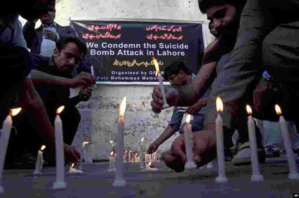 Members of a civil society group light candles during a vigil for the victims of Sunday's suicide bombing in Karachi, Pakistan.