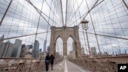 មនុស្សម្នាពាក់​ម៉ាស​ដើម្បី​ការពារ​កុំ​ឲ្យ​ឆ្លង​ជំងឺ​កូវីដ១៩ ខណៈ​ដែល​ពួកគេ​កំពុង​បណ្ដើរ​ឆ្កែ​របស់​ខ្លួន​កាត់​ស្ពាន Brooklyn ក្នុងទីក្រុង​ញូវយ៉ក រដ្ឋញូវយ៉ក សហរដ្ឋអាមេិក ថ្ងៃ​សុក្រ ថ្ងៃទី១០ ខែមេសា ឆ្នាំ២០២០។