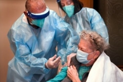FILE - Bob Atighechi administers the COVID-19 vaccination to Margaret Dubois, 87, a resident at The Reservoir nursing facility, Friday, Dec. 18, 2020, in West Hartford, Conn. (AP Photo/Stephen Dunn, Pool)