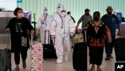 រូបឯកសារ៖ សមាជិក​អាកាស​យានិក​ក្នុង​ឈុត​ការពារ​ និង​អ្នកដំណើរ​ដើរ​នៅ​អាកាស​យានដ្ឋាន​អន្តរជាតិ Los Angeles ក្នុង​ទីក្រុង Los Angeles រដ្ឋ California នៅ​ថ្ងៃទី៣០ ខែវិច្ឆិកា ឆ្នាំ២០២១។