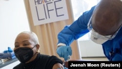 Une femme reçoit une dose du vaccin Pfizer-BioNTech contre la maladie COVID-19 à l'hôpital de Harlem à New York, aux États-Unis, le 25 février 2021. 