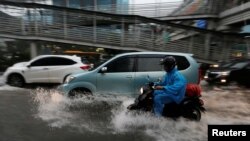 មនុស្ស​ម្នាក់​ជិះ​ម៉ូតូ​កាត់​ទឹក​ជំនន់​​លើ​ផ្លូវក្នុង​សង្កាត់​ពាណិជ្ជកម្ម​​មួយ​ក្នុង​ទីក្រុង ហ្សាការតា ប្រទេស​ឥណ្ឌូនេស៊ី​ កាល​ពី​ថ្ងៃ​ទី​១១ ខែ​ធ្នូ ឆ្នាំ ២០១៧។