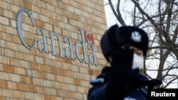 A police officer gestures at the photographer outside the embassy of Canada in Beijing, China, December 12, 2018. 