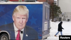 Seorang pria berjalan melewati bus yang terparkir di luar markas kampanye tim Donald Trump di New Hampshire, pada 20 Januari 2024. (Foto: Reuters/Kevin Lamarque)