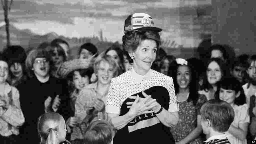 Đệ nhất Phu nhân Nancy Regan đội nón và cầm một chiếc áo của học sinh khi đến thăm trường Latin ở Chicago, ngày 14 tháng 5,1982.