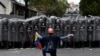 FILE - A man kneels in front of police blocking a march called by opposition leader Juan Guaido, in Caracas, Venezuela, March 10, 2020. 