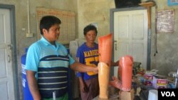 Kyaw Win and his colleague, both former Karenni fighters who lost legs to landmines, look at prosthetic legs in their workshop in Loikaw, in Karenni State in Myanmar. (P. Vrieze/VOA)