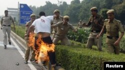 La policía intenta sofocar el fuego en un tibetano que se inmoló frente a la embajada China Nueva Delhi. 