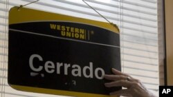 Un oficinista de Western Union coloca el cartel de cerrado en su último día de trabajo en La Habana, Cuba, el lunes 23 de noviembre de 2020.