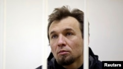 Greenpeace activist Tomasz Dziemianczuk of Poland looks out from a defendants' cage during a court session in St. Petersburg, Russia, Nov. 19, 2013.