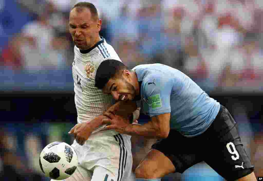 Uruguay's Luis Suarez, right, and Russia's Sergei Ignashevich fight for the ball during the group A match between Uruguay and Russia at the 2018 soccer World Cup at the Samara Arena in Samara, Russia.