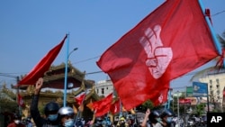 Engineers carry flags bearing the three-fingers salute as they drive their motorcycles during an anti-coup protest in Mandalay, Myanmar on Thursday March 25, 2021. 