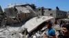 People inspect the rubble of a destroyed residential building which was hit by Israeli airstrikes, in Gaza City, May 12, 2021.
