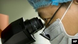 На Фото: лікар у Китаї дивиться у мікроскоп