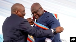 Rais mstaafu Joseph Kabila akimvisha kitambaa maalum Rais Felix Tshisekedi ikiwa ni ishara ya kumkabidhi madaraka baada ya kuapishwa Kinshasa, DRC, Alhamisi Jan. 24, 2019. 