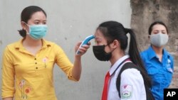 រូបឯកសារ៖ សិស្សម្នាក់ត្រូវបានវ៉ាស់កម្តៅមុនពេលចូលរៀននៅសាលារៀនមួយក្នុងក្រុងហាណូយ ប្រទេសវៀតណាម កាលពីថ្ងៃទី០៤ ខែឧសភា ឆ្នាំ២០២០។ 