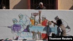 Man applies finishing touches to graffiti representing a vaccine in Kolkata