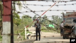 FILE - A Myanmar police officer stands watch as journalists arrive in Shwe Zar village in the suburb of Maungdaw town, northern Rakhine state of Myanmar, Sept. 6, 2017. 