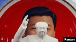 北京天安門附近一個紀念品商店裡毛澤東的塑像擺在習近平紀念畫盤的前面。 （2018年3月1日） 