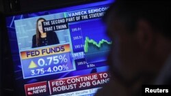 A screen displays the Fed rate announcement as traders work on the floor of the NYSE in New York