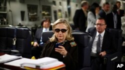Photo d'archives (18 octobre 2011): Hillary Rodham Clinton, alors secrétaire d'Etat, vérifie son Blackberry dans un avion militaire l'emmenant de Malte, en mer Méditerranée, à Tripoli, en Libye.
