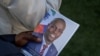 Una persona sostiene una foto del difunto presidente haitiano Jovenel Moise, quien fue asesinado a tiros el año pasado, durante su funeral en la casa de su familia en Cabo Haitiano, Haití, el 23 de julio de 2021.