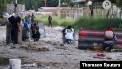 Los manifestantes se protegen durante una protesta y dicen que hay brutalidad policial y uso excesivo de la fuerza contra protestas pacíficas, en Yumbo.