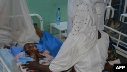 Une mère s'occupe de son enfant malnutri au service de pédiatrie d'un hôpital de Ndjamena, Tchad, le 15 février 2022.