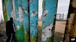 Un hombre mira a través del muro fronterizo entre la ciudad de Tijuan, México, y San Diego, en Estados Unidos, el 19 de enero de 2021..