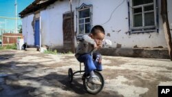 Alif Baqytali plays on a tricycle at his home in Shonzhy, Kazakhstan on June 13, 2020. Baqytali's mother, Gulnar Omirzakh, says she was forced to get a contraceptive device, and that authorities threatened to detain her if she didn't pay a large fine for giving birth to him. (AP)