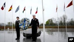 Dos militares se ven bajo las banderas de los estados miembros de la OTAN durante una ofrenda floral en la sede de la alianza en Bruselas, el jueves 4 de abril de 2024. La OTAN celebra el jueves 75 años desde la firma de su tratado fundacional.