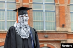 A Palestinian student, who plans to return to his homeland after graduation and who wishes to remain anonymous, poses for a portrait while wearing a keffiyeh along with his commencement cap at the Auraria Campus in Denver, Colorado, U.S., May 10, 2024. (REUTERS/Kevin Mohatt)