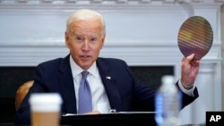 2021年4月12日在华盛顿白宫举行的有关半导体和供应链产业韧性的CEO峰会上，美国总统拜登举起一块硅片。