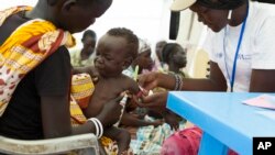 FILE - In this photo of Friday, July 25, 2014, a child with suspected malnutrition is examined at IMC nutrition program clinic in Malakal, South Sudan. Researchers said this week that one-third of young children living in developing nations are failing to meet basic mental development milestones.