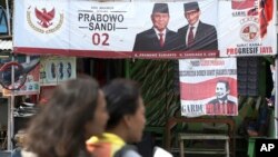 A couple rides a motorcycle past a campaign banners for Indonesian presidential candidate Prabowo Subianto, left, and his running mate Sandiaga Uno in Jakarta, Indonesia, Thursday, Jan. 17, 2019. 