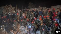Rescue teams work at a site hit by a rocket during fighting over the breakaway region of Nagorno-Karabakh, in the city of Ganja, Azerbaijan, early Oct. 17, 2020. 