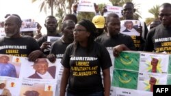 FILE - Anti-slavery militants hold a banner whose message translates as "No to slavery and racism, no to the regime of the general dictator Mohamed Ould Abdel Aziz" as they demonstrate, Aug. 3, 2016, in Dakar against the imprisonment of fellow activists in Mauritania.