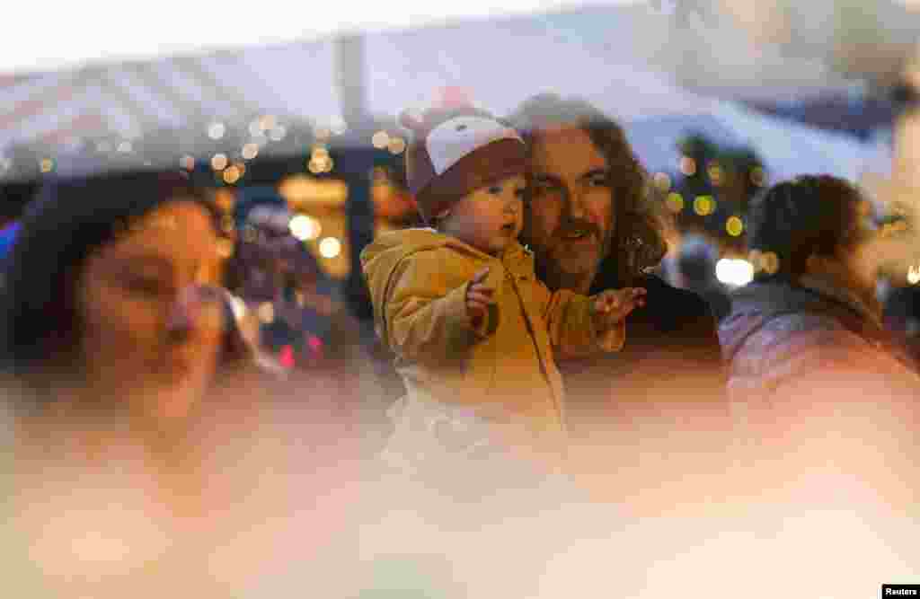 A man holds a baby, at the famous Nuernberger Christkindlesmarkt (Christ Child Market), one of the world's oldest Christmas markets, on the day of its opening ceremony in Nuremberg, Germany.