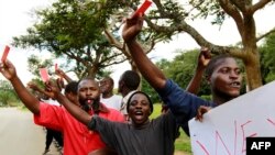 FILE - Roman Catholic priest Frank Bwalya (in red) and supporters hold red cards to display their displeasure with the government as they attend a rally in front of the National Assembly, in Lusaka, Zambia, March 22, 2011.