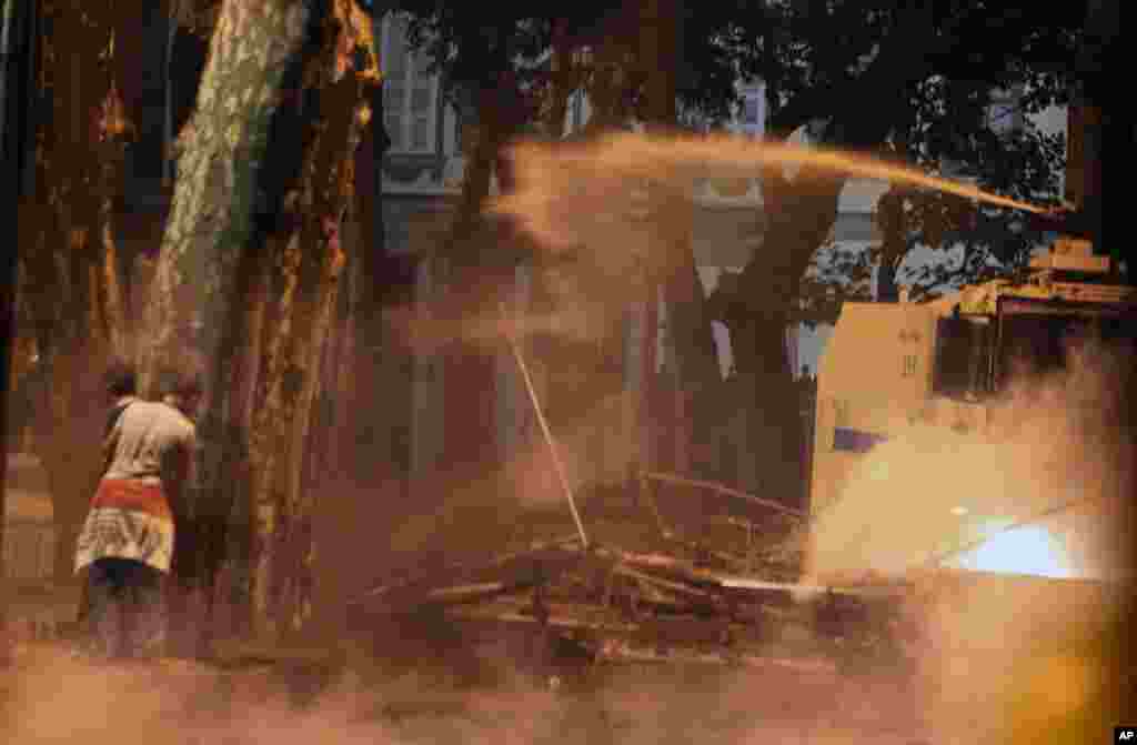 Police use a water cannon as protesters take cover behind a tree during nationwide anti-government protests in Besiktas, Istanbul, June 2, 2013.
