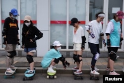 Members of Beijing Girls Surfskating Community stand on skateboards as they attend a training session for beginners, outside the National Sports Stadium in Beijing, China June 19, 2022. (REUTERS/Tingshu Wang)