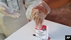 Seorang perempuan yang mengenakan sarung tangan plastik memberikan suaranya saat pemilihan kepala daerah di sebuah TPS di Tangerang, Rabu, 9 Desember 2020. (AP//Tatan Syuflana)