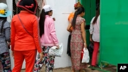 Cambodian garment workers return to a factory after their lunch break in Phnom Penh, Cambodia Thursday, March 12, 2015. 