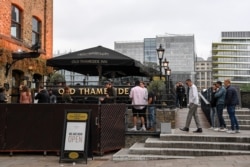 People sit and drink, outside a pub on the south bank of river Thames, as the capital is set to reopen after the lockdown due to the coronavirus outbreak, in London, July 4, 2020.