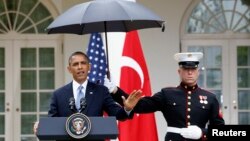 Infantes de marina protegen de la lluvia al presidente Barack Obama, en la Rosaleda de la Casa Blanca.