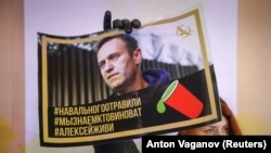 Ruska opozicionarka za slikom Alekseja Navalnog u Sankt Peterburgu (Foto: REUTERS/Anton Vaganov)