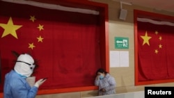 身穿防护服的医护人员在武汉的一所方舱医院里安慰一名病患。（2020年2月27日）