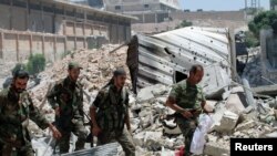 Forces loyal to Syria's President Bashar al-Assad walk with their weapons past rubble after they advanced on the southern side of the Castello road in Aleppo, Syria, in this handout picture provided by SANA on July 28, 2016. 